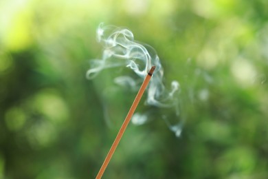 Photo of Incense stick smoldering on green blurred background