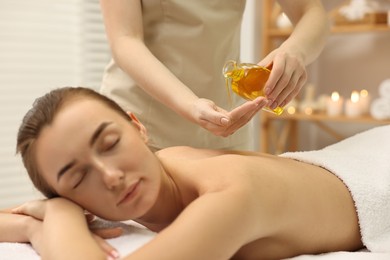 Aromatherapy. Beautiful woman receiving back massage with oil in spa salon