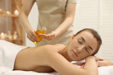 Aromatherapy. Beautiful woman receiving back massage with oil in spa salon