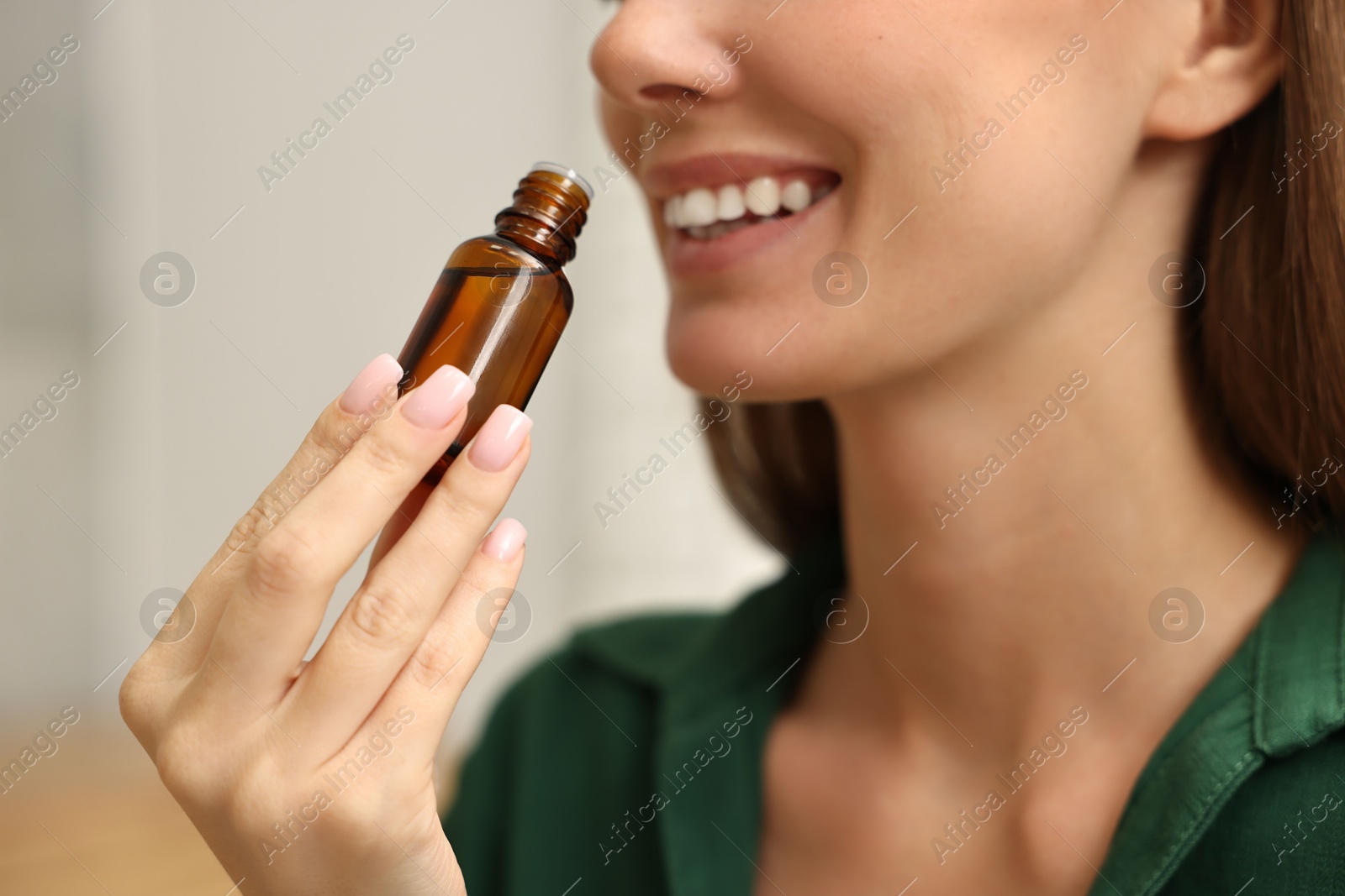 Photo of Aromatherapy. Woman with bottle of essential oil on light background, closeup