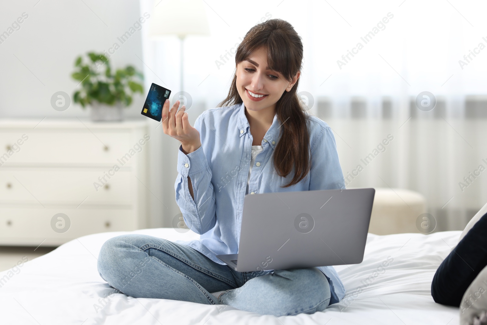 Photo of Online banking. Smiling woman with credit card and laptop paying purchase at home