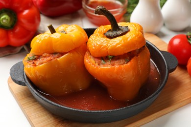 Photo of Tasty stuffed peppers in pan on light table, closeup