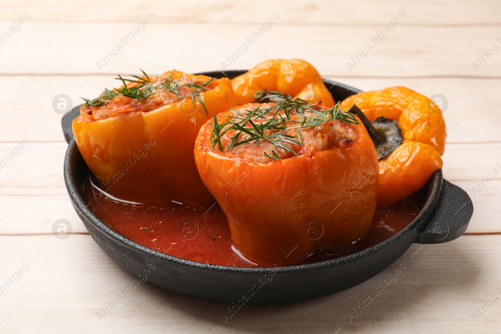 Photo of Tasty stuffed peppers in pan on light wooden table, closeup