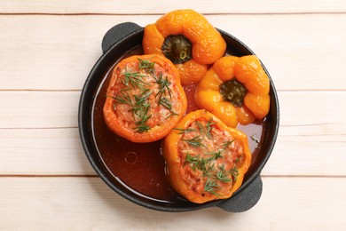 Photo of Tasty stuffed peppers in pan on light wooden table, top view