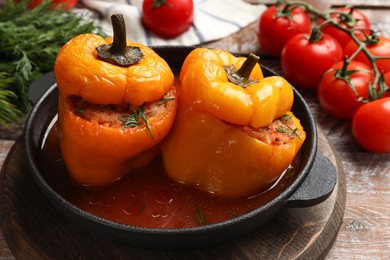 Photo of Tasty stuffed peppers in pan and products on wooden rustic table, closeup