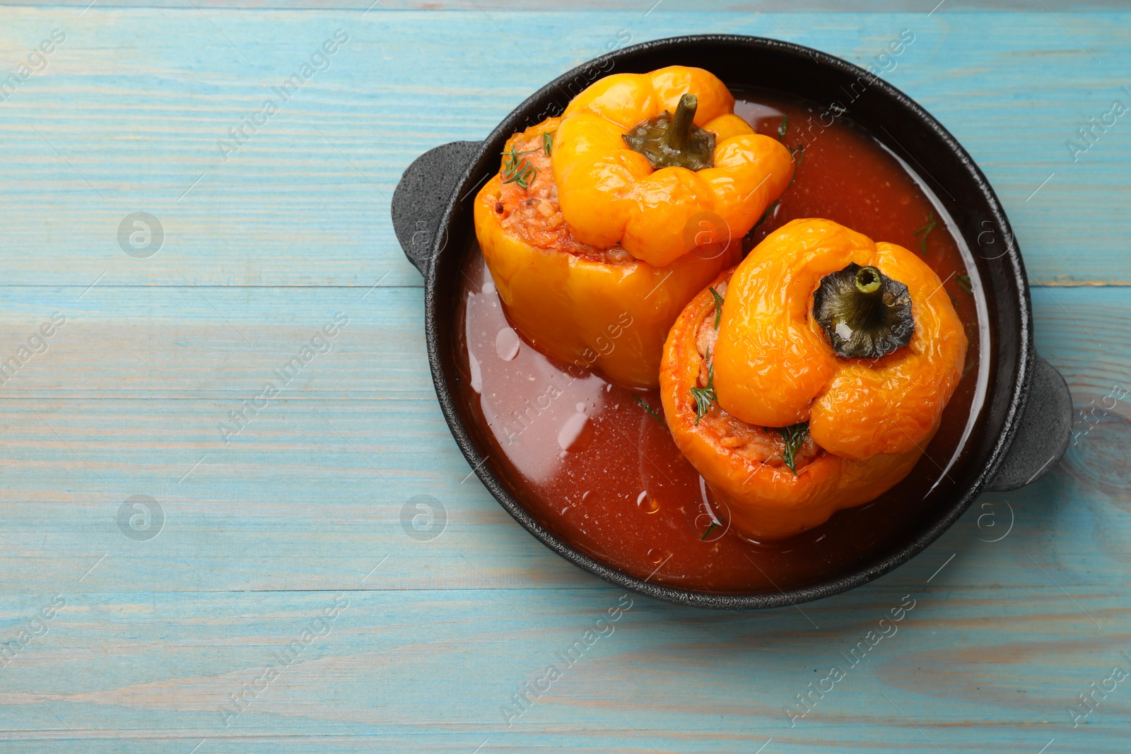 Photo of Tasty stuffed peppers on light blue wooden table, top view. Space for text