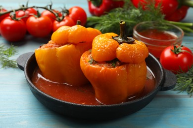 Photo of Tasty stuffed peppers and products on light blue wooden table, closeup