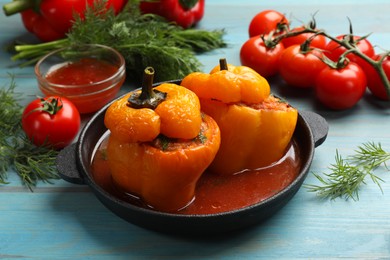 Photo of Tasty stuffed peppers and products on light blue wooden table, closeup