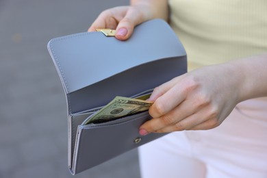 Photo of Woman holding purse with banknotes outdoors, closeup