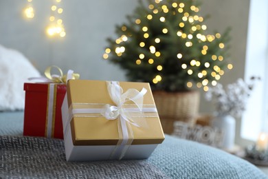 Photo of Christmas gift boxes on bed in festive interior