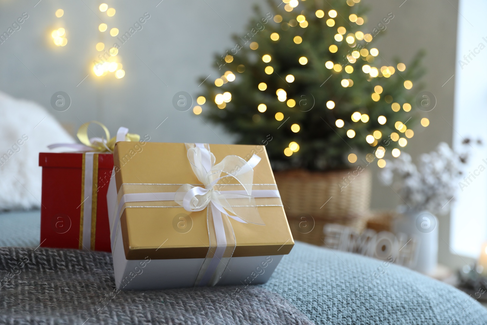 Photo of Christmas gift boxes on bed in festive interior