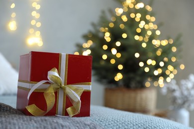 Photo of Christmas gift box on bed in festive interior