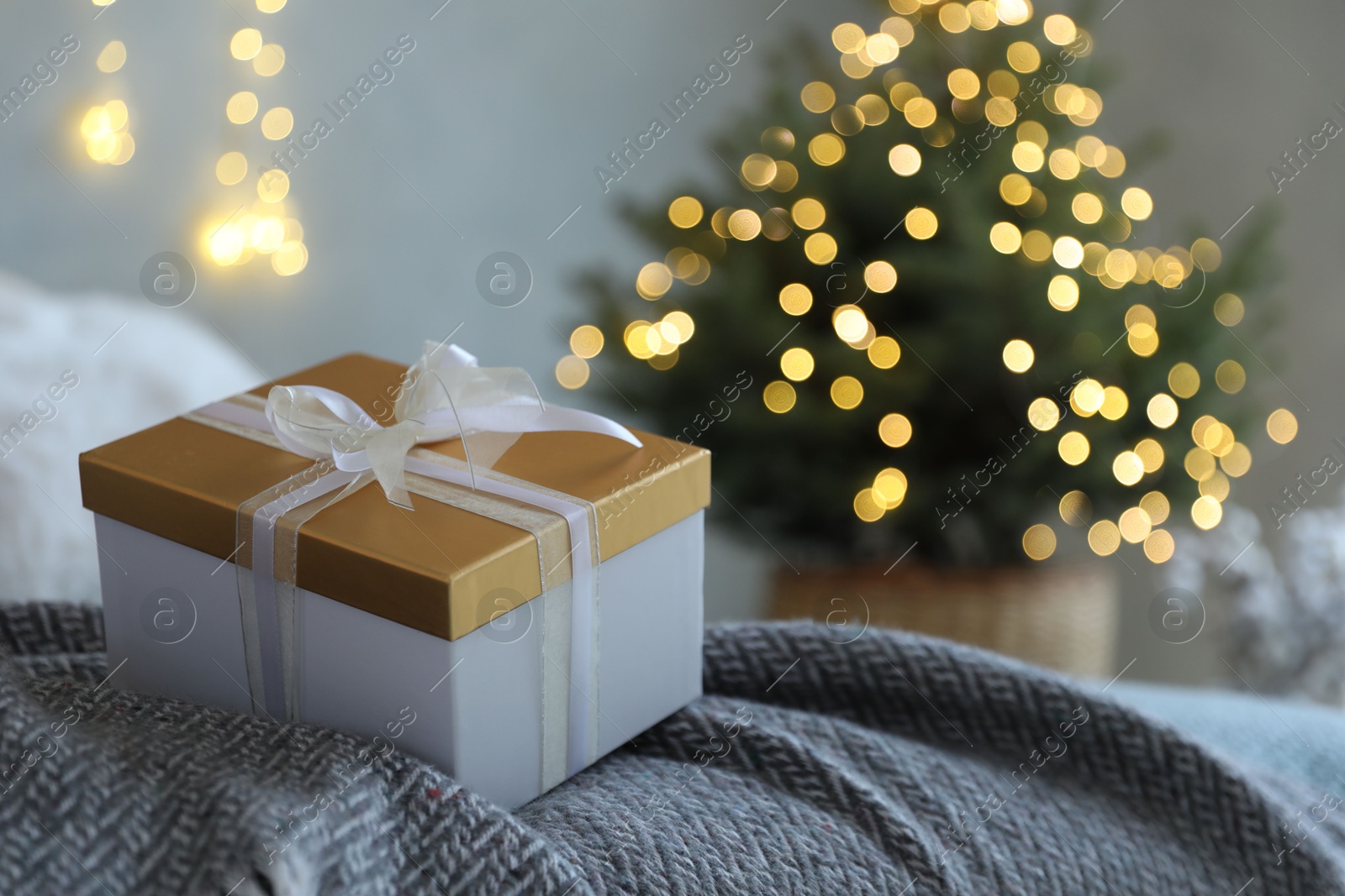 Photo of Christmas gift box on bed in festive interior