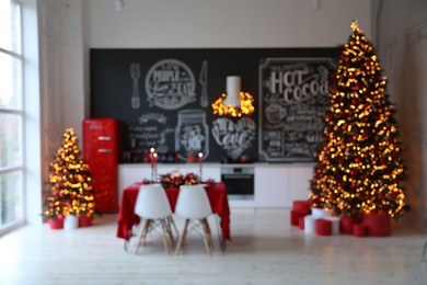 Photo of Stylish kitchen interior with festive table and  decorated Christmas trees, blurred view