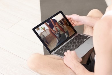 Online fitness trainer. Man watching tutorial on laptop indoors, closeup. Space for text