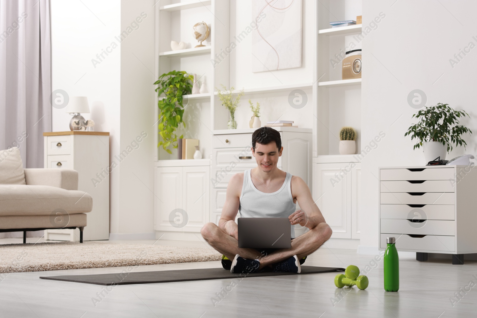 Photo of Online fitness trainer. Man watching tutorial on laptop indoors