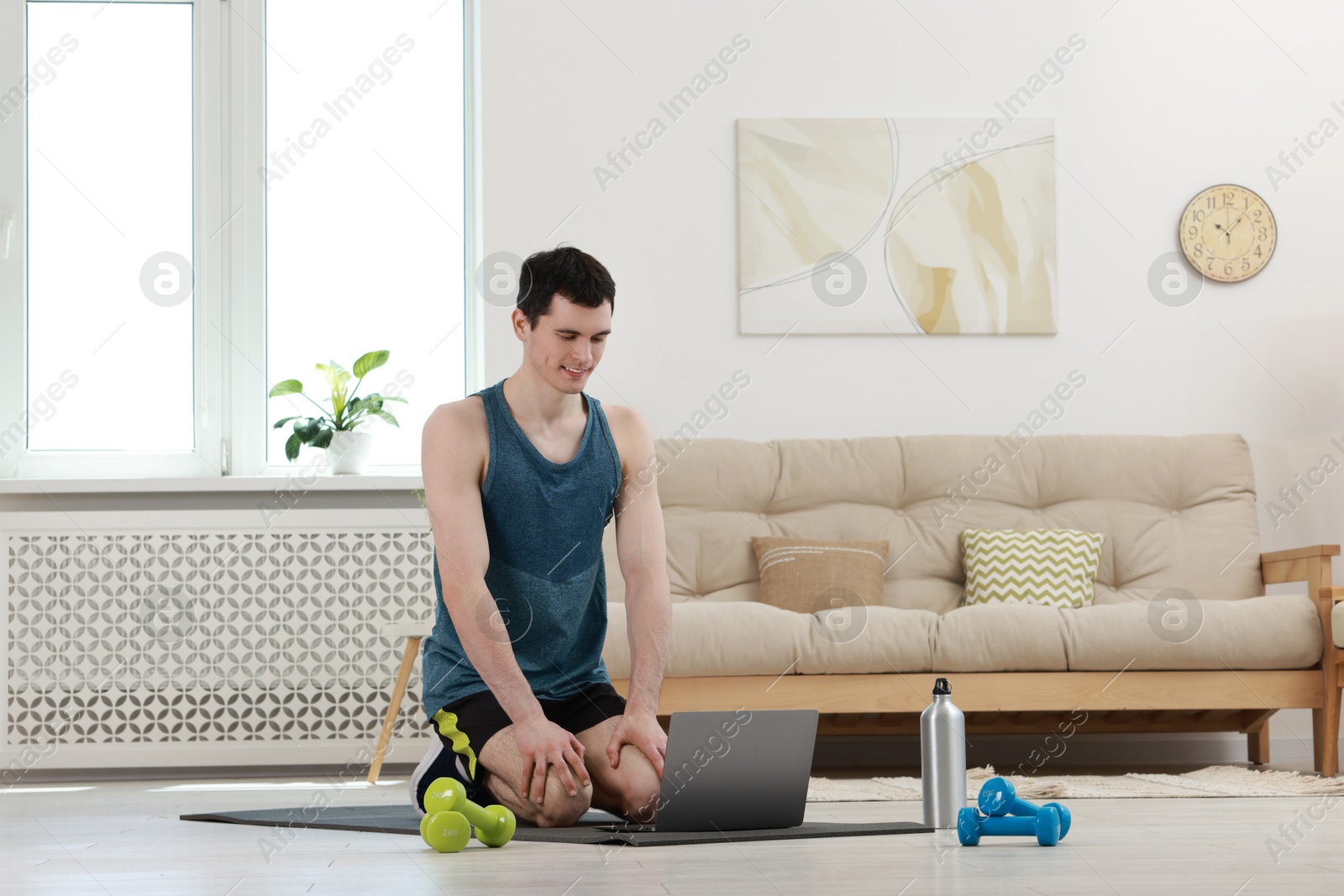 Photo of Online fitness trainer. Man watching tutorial on laptop indoors