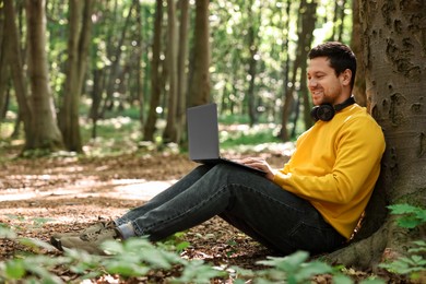 Photo of Smiling traveler working with laptop outdoors. Remote job