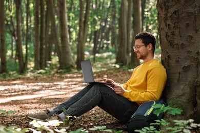 Smiling traveler working with laptop outdoors. Remote job