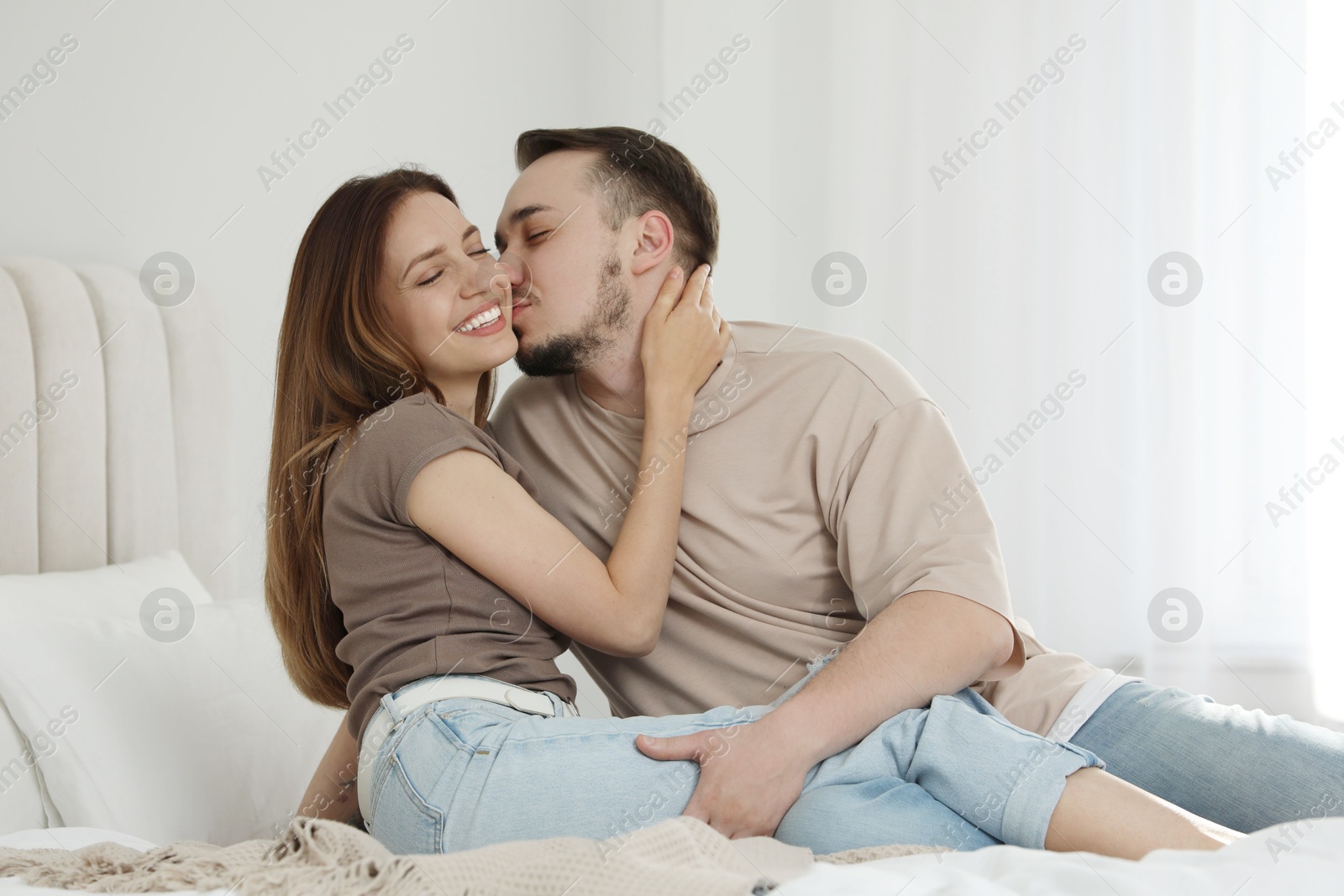 Photo of Man kissing his girlfriend on bed at home