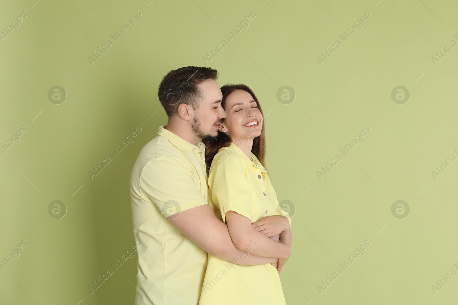 Photo of Man hugging his happy girlfriend on green background