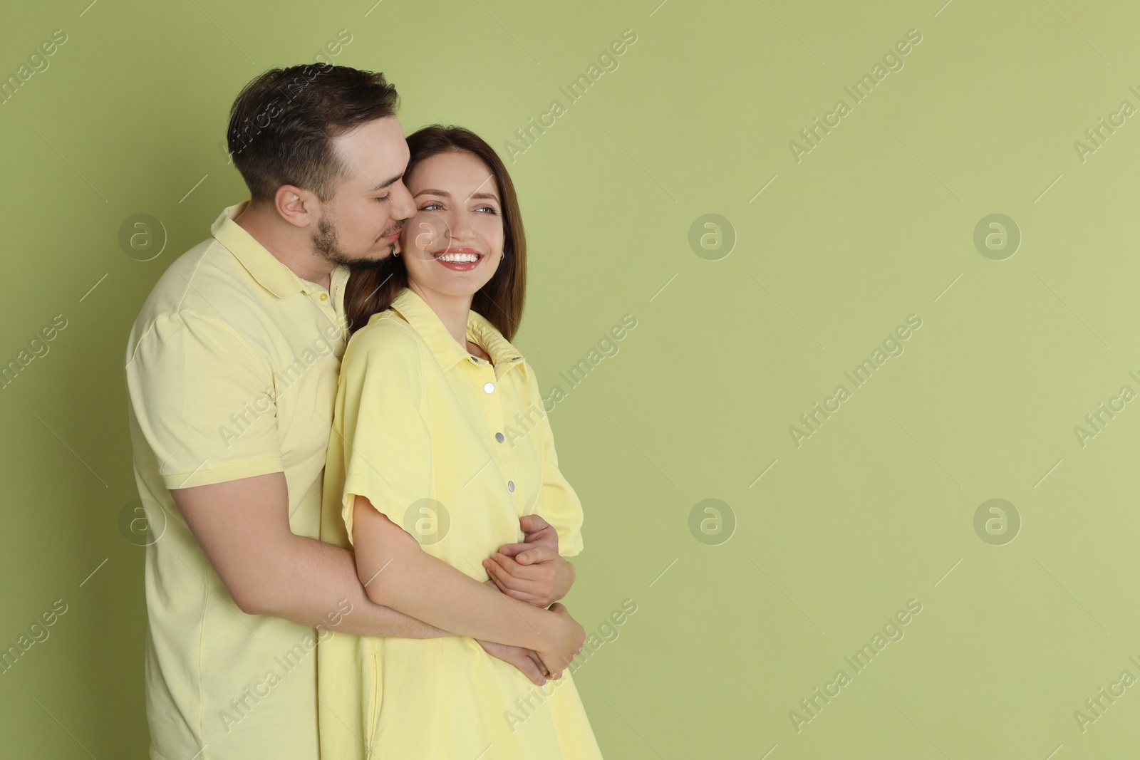 Photo of Man hugging his happy girlfriend on green background. Space for text