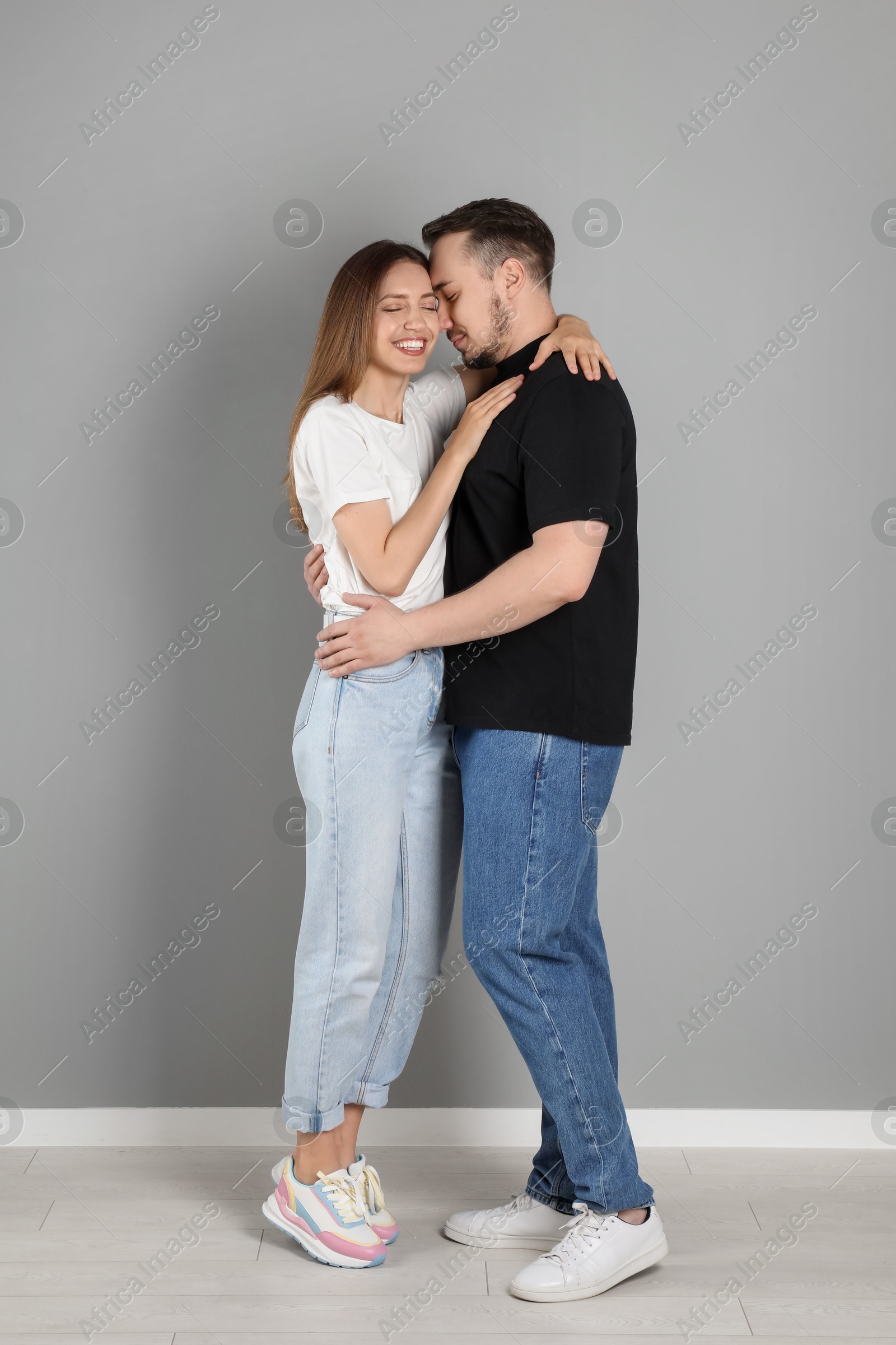 Photo of Happy couple hugging near grey wall. Strong relationship