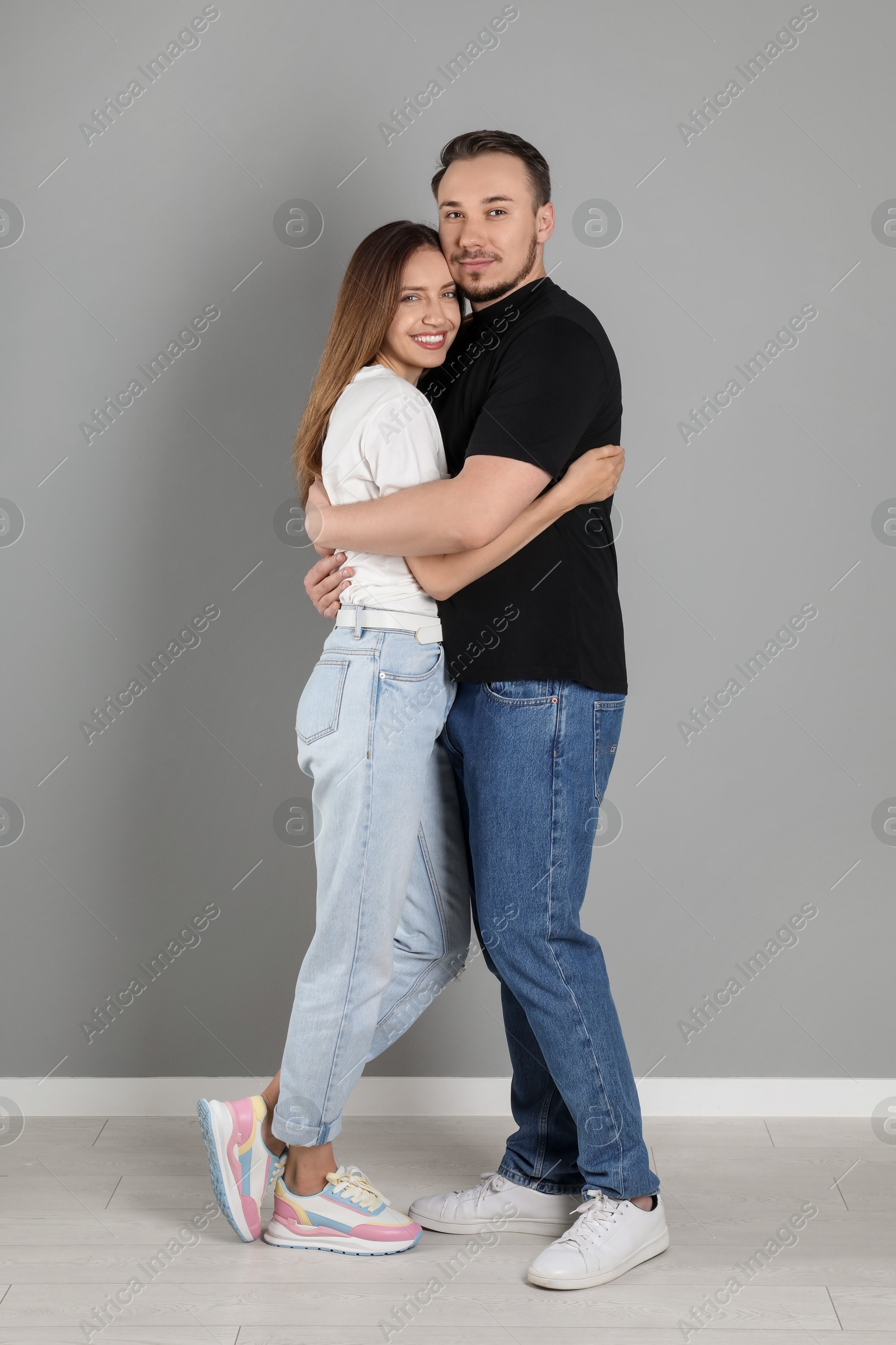 Photo of Happy couple hugging near grey wall. Strong relationship