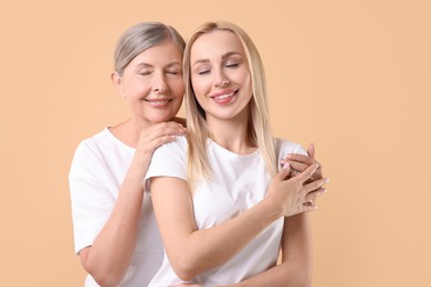 Photo of Family portrait of young woman and her mother on beige background