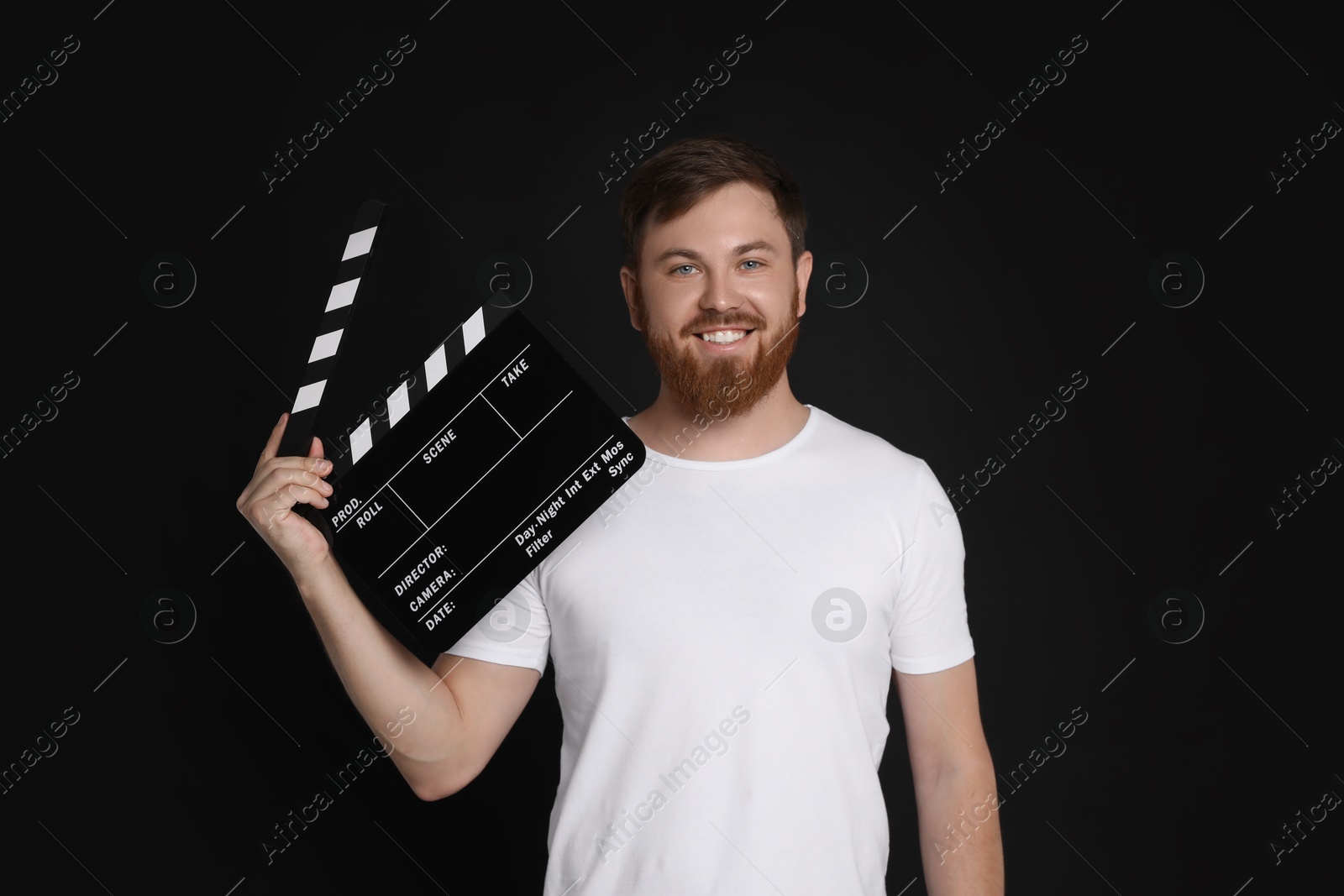 Photo of Making movie. Smiling man with clapperboard on black background
