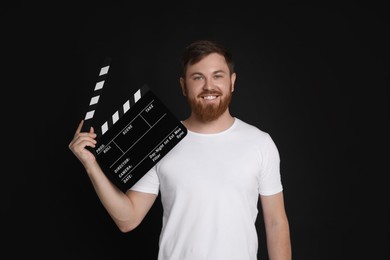 Making movie. Smiling man with clapperboard on black background
