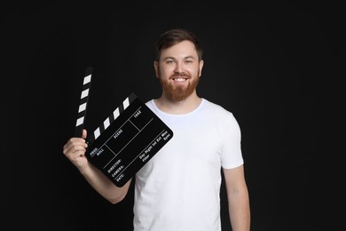 Making movie. Smiling man with clapperboard on black background