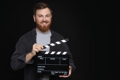 Photo of Making movie. Smiling man with clapperboard on black background. Space for text