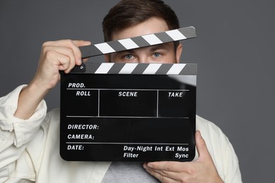 Making movie. Man with clapperboard on grey background