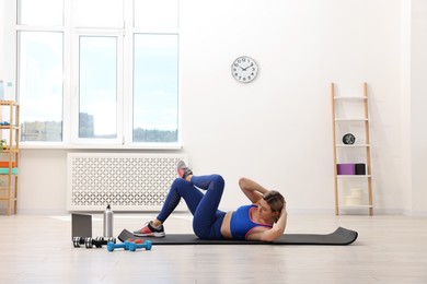 Photo of Online fitness trainer. Woman pumping up abs near laptop at home