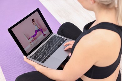 Photo of Online fitness trainer. Woman watching tutorial on laptop indoors, above view