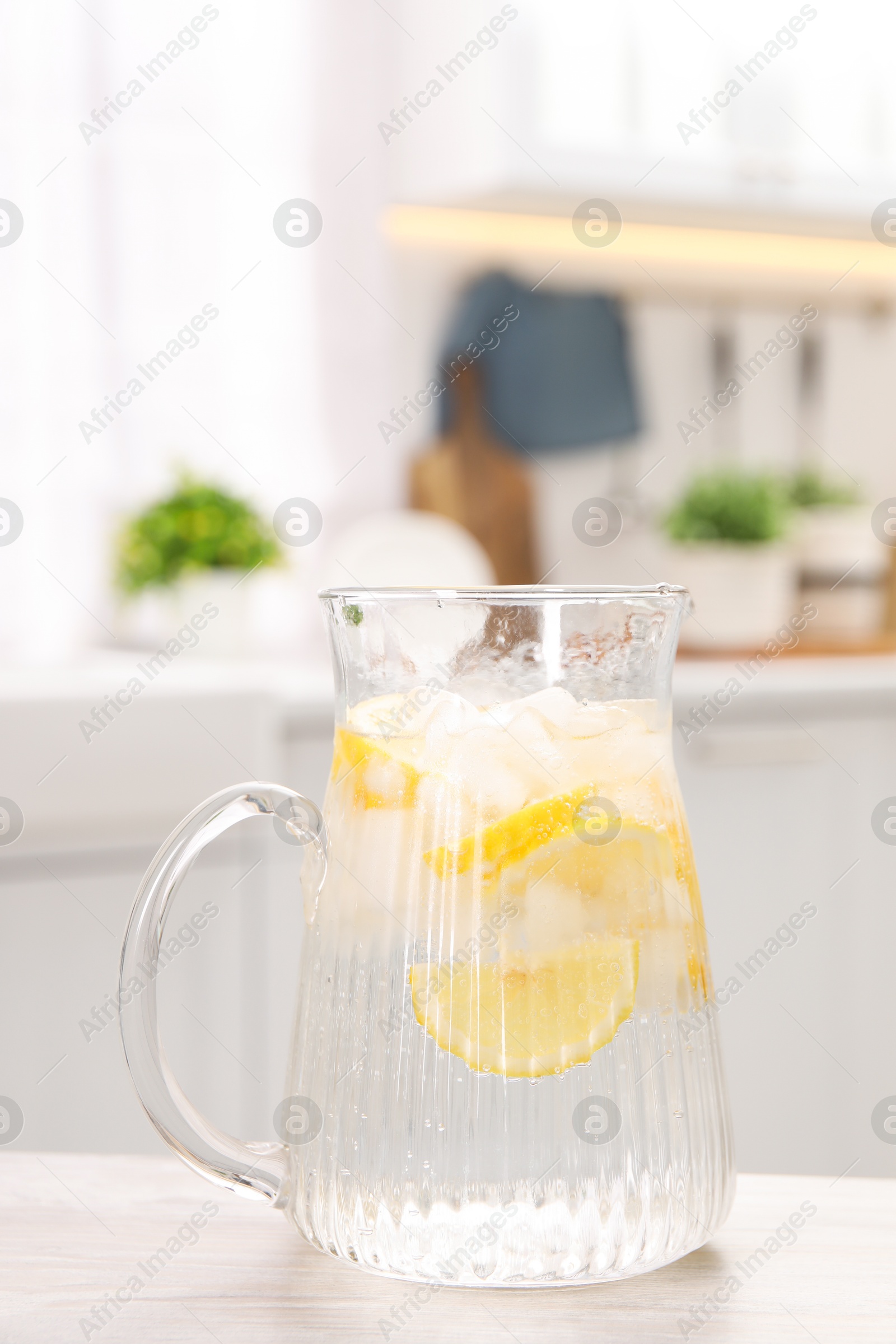 Photo of Freshly made lemonade in jug on white wooden table indoors