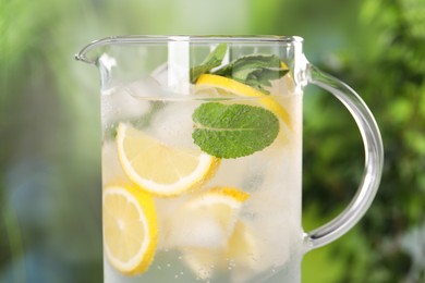 Photo of Freshly made lemonade with mint in jug outdoors, closeup