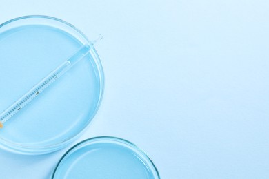 Photo of Transfer pipette and petri dishes on light blue background, flat lay. Space for text