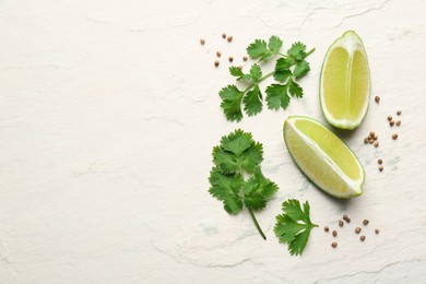 Fresh coriander leaves, dried seeds and lime wedges on light textured table, flat lay. Space for text