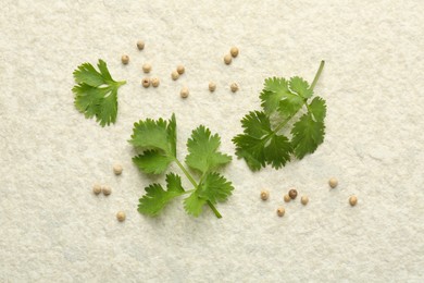 Photo of Fresh coriander leaves and dried seeds on light textured table, flat lay