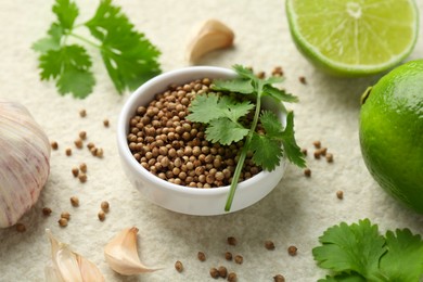 Fresh coriander leaves, dried seeds, garlic and limes on light textured table, closeup