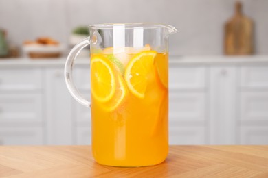 Photo of Freshly made lemonade in jug on wooden table in kitchen