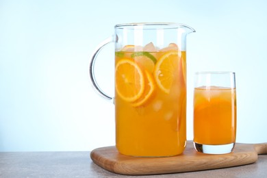 Photo of Freshly made lemonade in jug and glass on grey table against light blue background, space for text