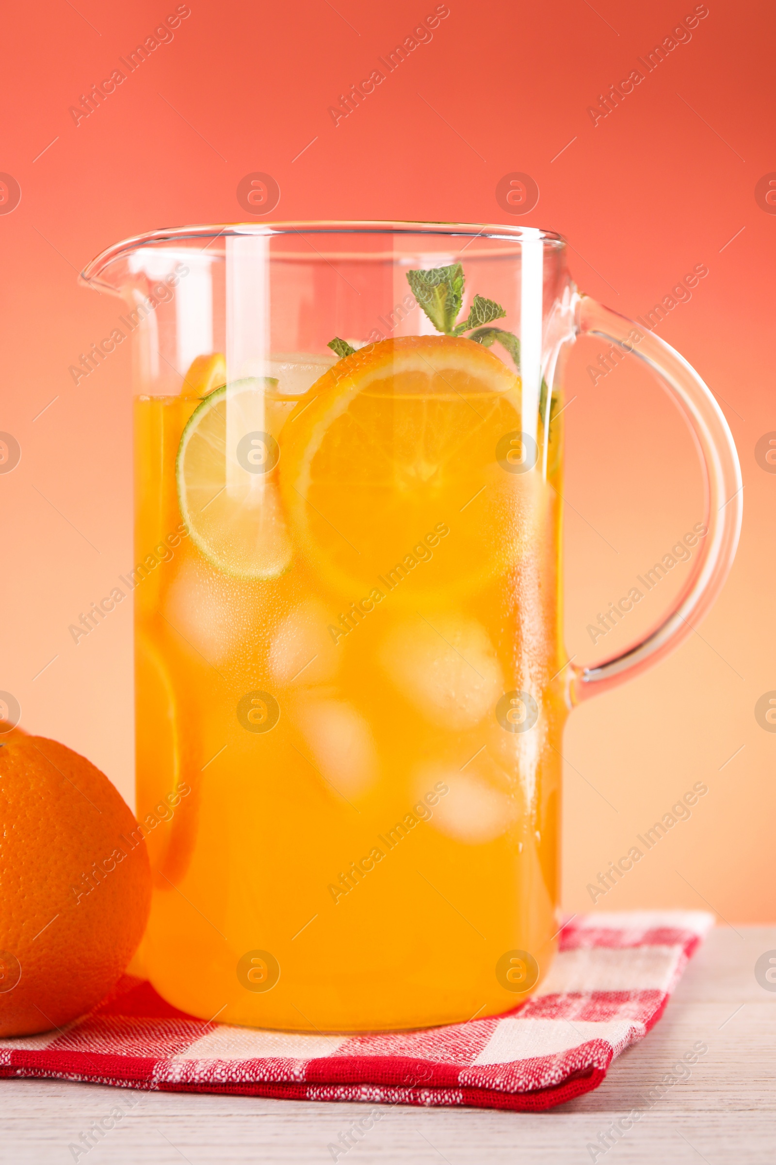 Photo of Freshly made lemonade in jug and orange on light wooden table