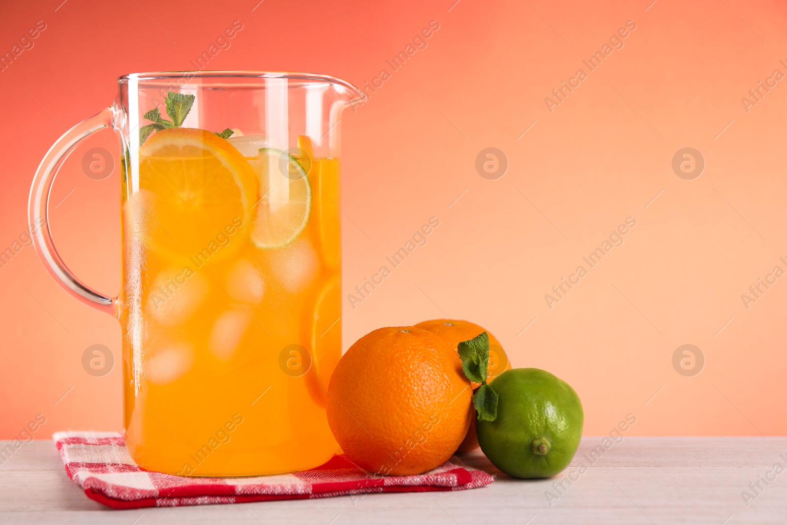 Photo of Freshly made lemonade in jug and citrus fruits on light wooden table