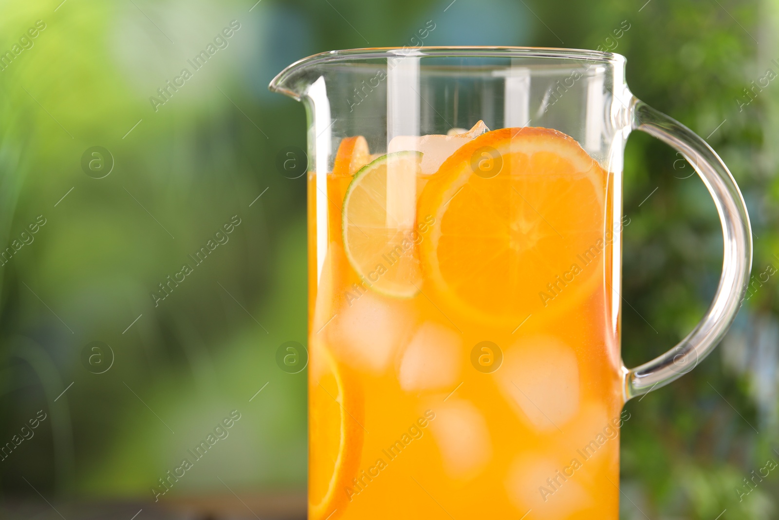 Photo of Freshly made lemonade in jug outdoors, space for text