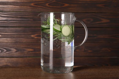 Photo of Refreshing cucumber water with rosemary in jug on wooden table