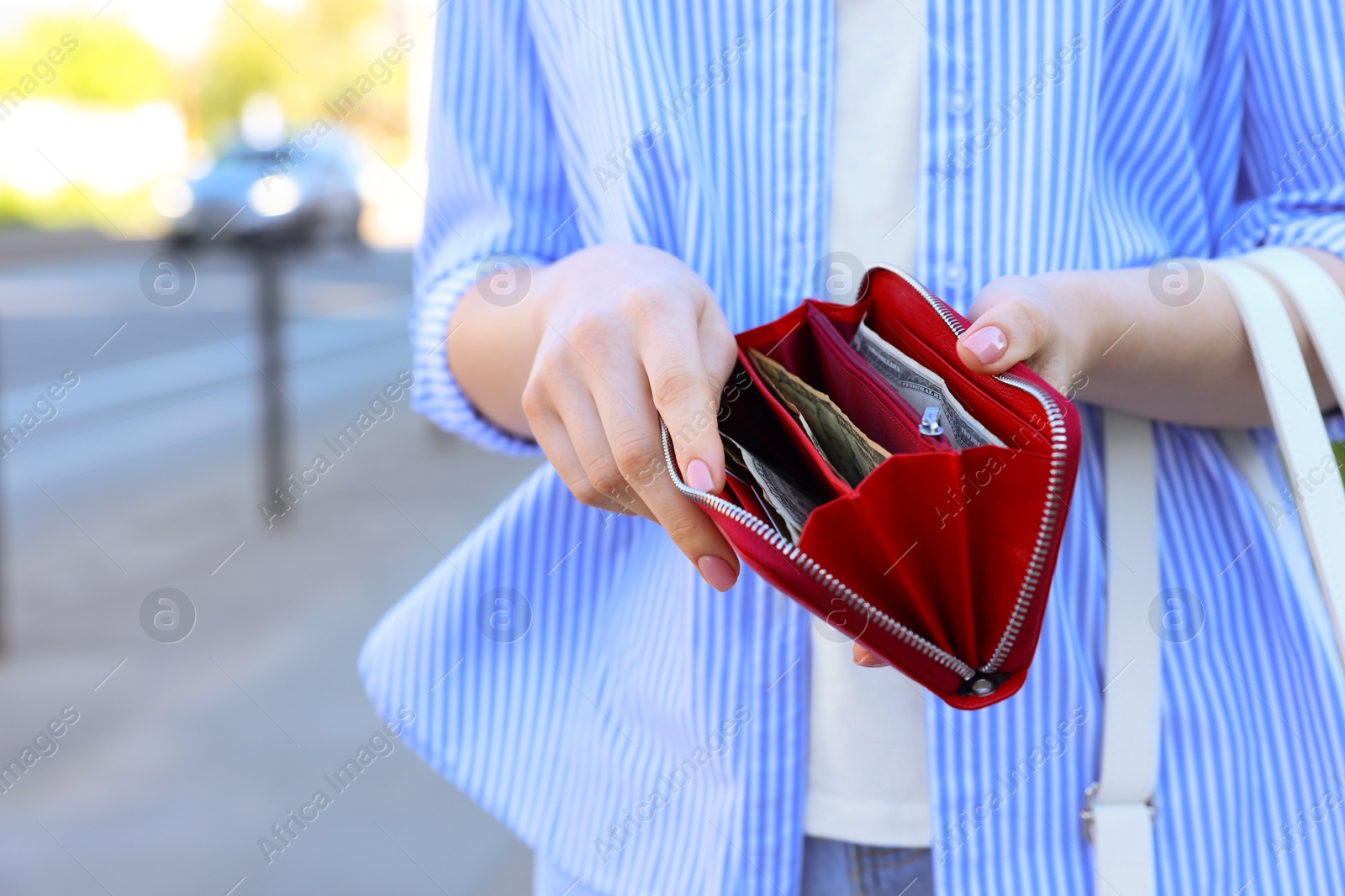 Photo of Woman holding purse with banknotes outdoors, closeup