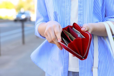 Woman holding purse with banknotes outdoors, closeup